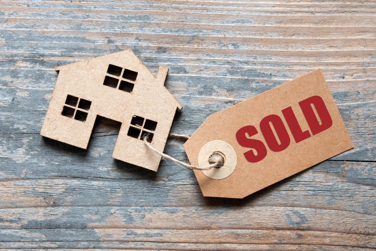 Pre-purchase building inspections - a wooden flat house shape on a desk with a sold paper tag